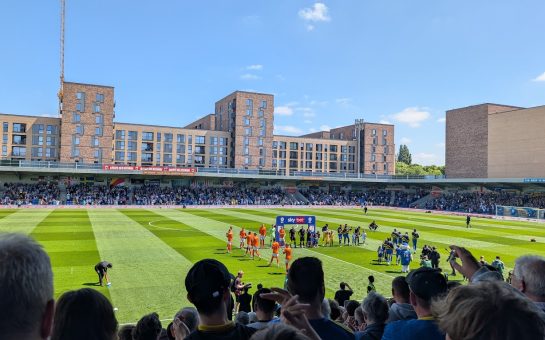 An image of AFC Wimbledon's Plough Lane stadium interior as the teams walk out onto the pitch.