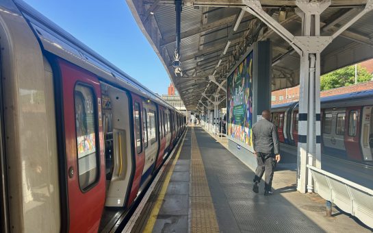 Tube Train at Wimbledon station. Man walking across.