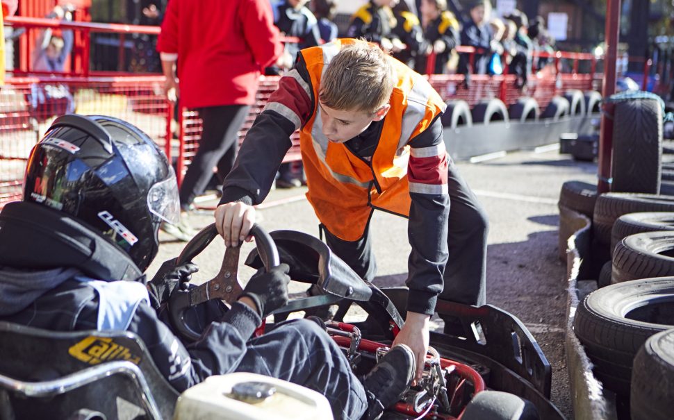 A karting volunteer helping a young karter.