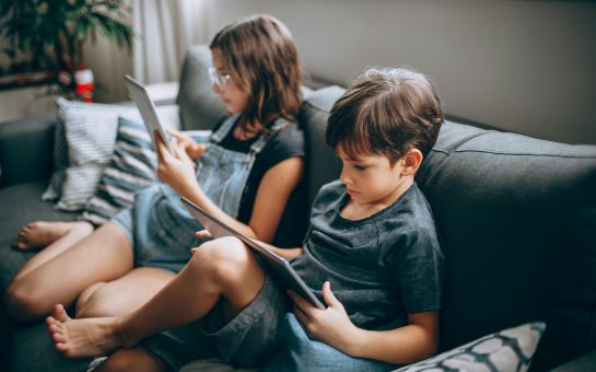 Two children sat on their phones