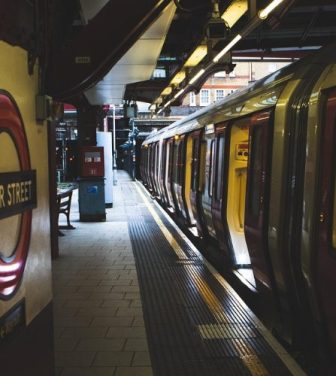 A darkly-lit undeground station with a train with open doors.
