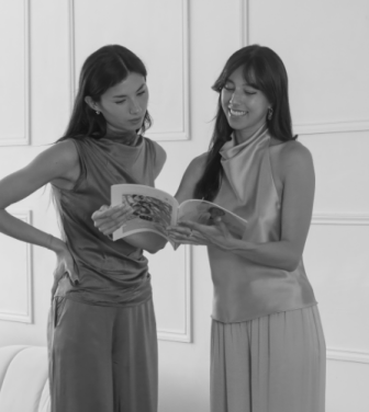 Two sisters holding a magazine whilst smiling.