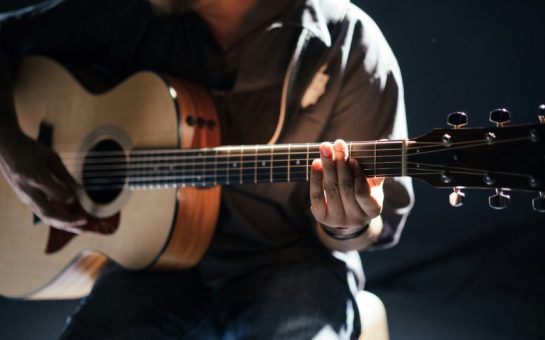 A photo of a man playing an acoustic guitar.