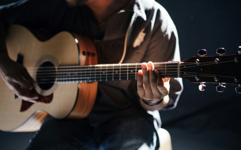 A photo of a man playing an acoustic guitar.