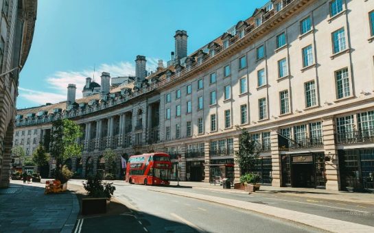 A photo of a red bus on Regent Street, Westminster on a summery day.