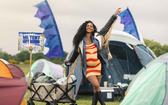 Image of a woman at a festival with a sign that says 'No tents left behind'.