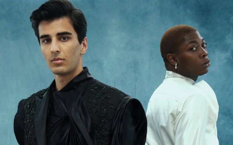 Two models wearing Spencer Thornton's graduate show collection on a blue textured backdrop.