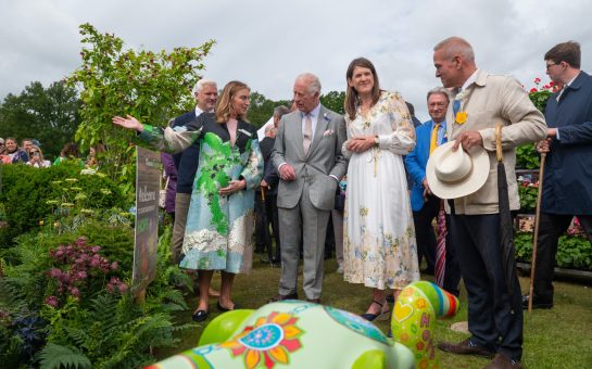King Charles at Windsor Flower Show admiring a garden alongside a group of attendees.