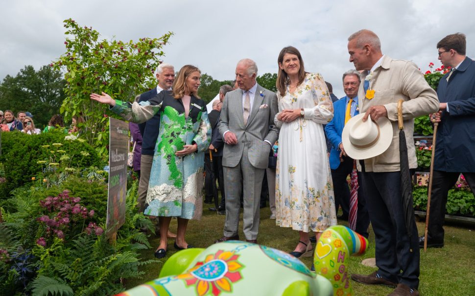 King Charles at Windsor Flower Show admiring a garden alongside a group of attendees.