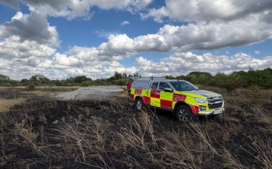 Fire vehicle parked on burnt heathland.