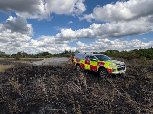 Fire vehicle parked on burnt heathland.