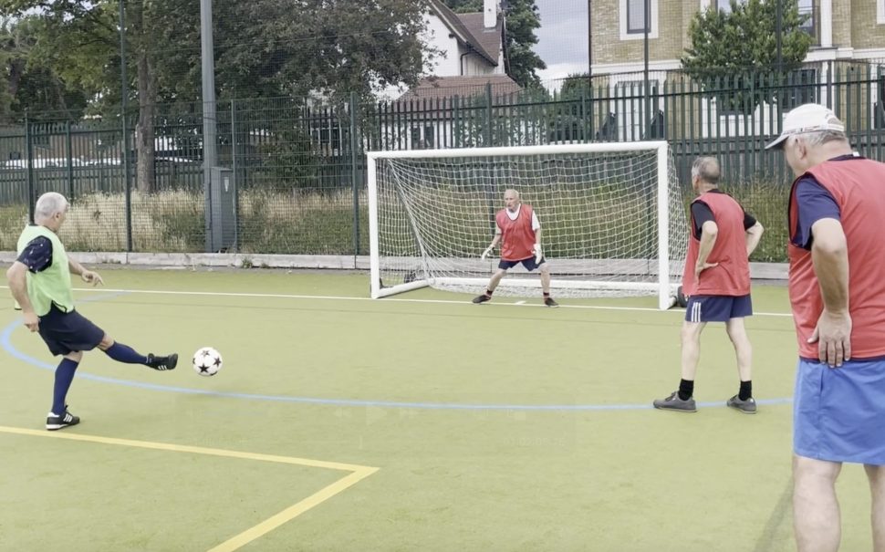 Walking football penalty - the ball is being struck towards goal.