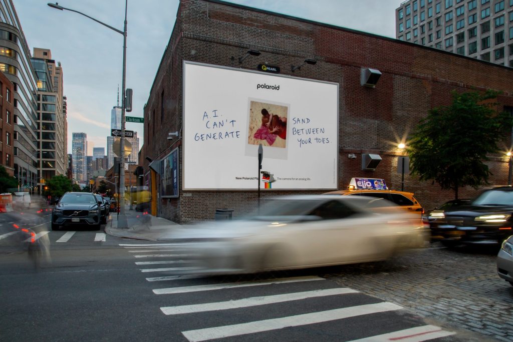 A polaroid campaign sign in New York with cars driving past