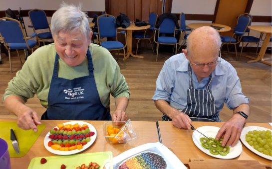 A photo of two Age UK community members at a food social event.