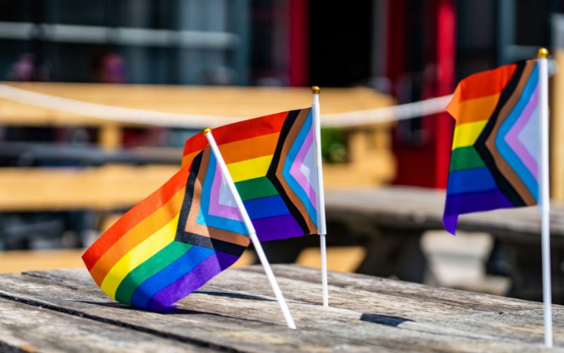 A picture of three small Pride flags on a bench.