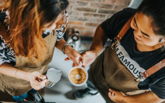 A photo of two people learning to make coffee.