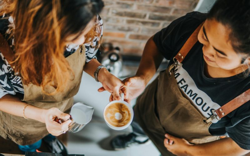 A photo of two people learning to make coffee.