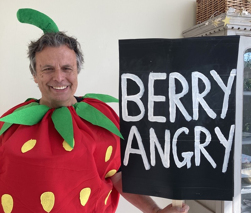 Simon Wright, campaigner for SWP group dressed as strawberry with a sign that says 'berry angry' . 