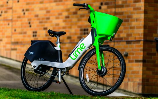 Lime Bikes rests on its stand in front of a brick wall
