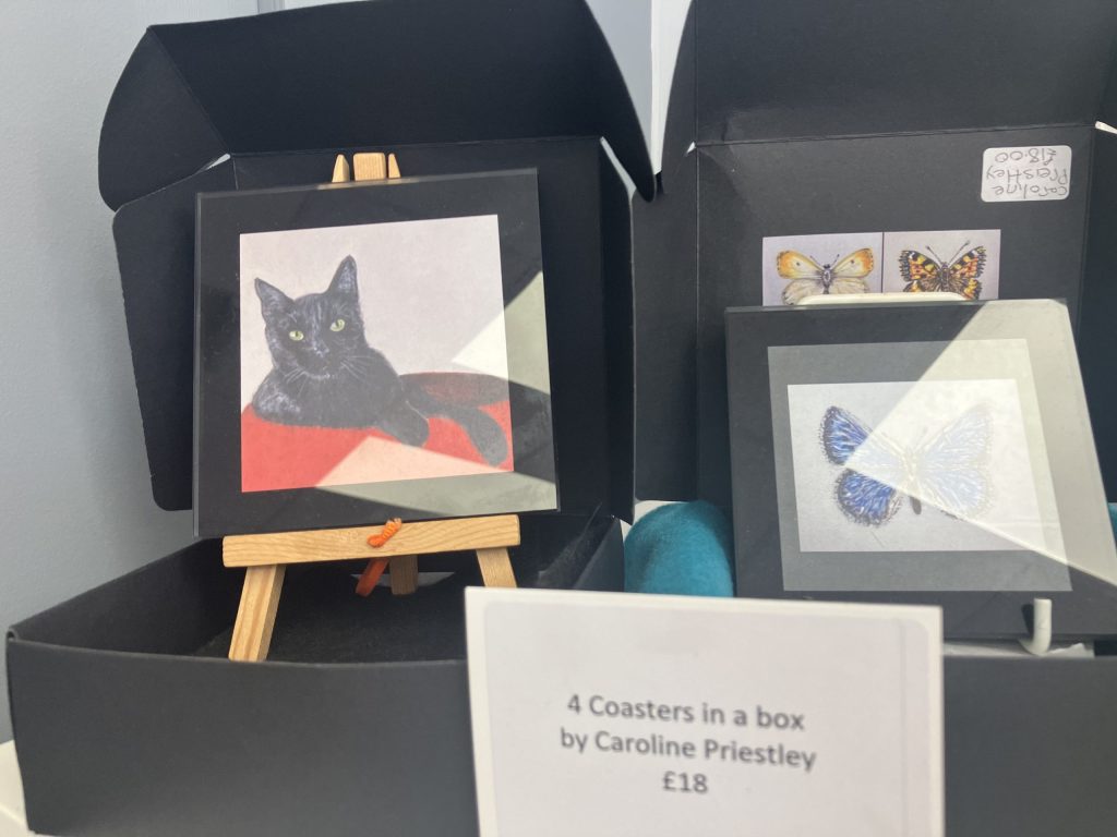 Artistic coasters including drawings of cats and butterflies on display at The People Hive