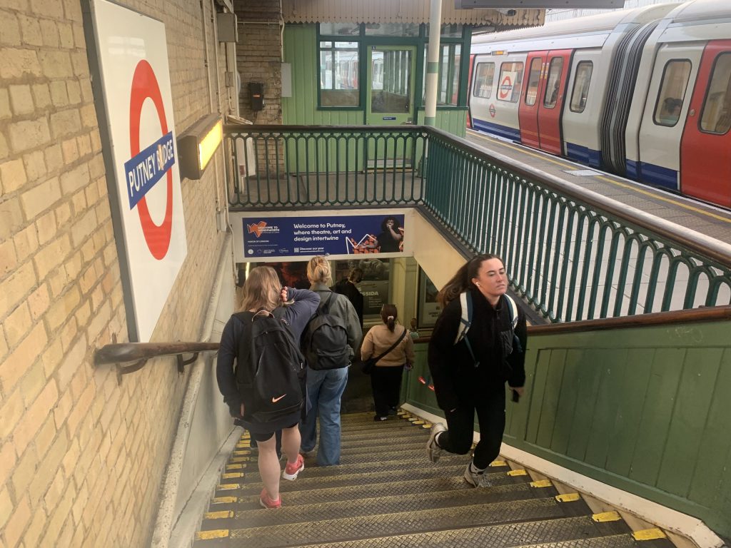 Woman runs up the stairs for the train at Putney Bridge station
