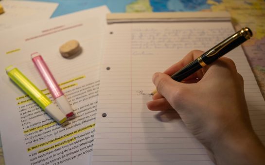 A person writing on paper (Credit: Free to use from Unsplash)