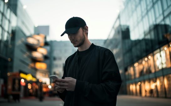 Man in black jacket wearing black fitted cap while using phone (Credit: Free to use from Unsplash)