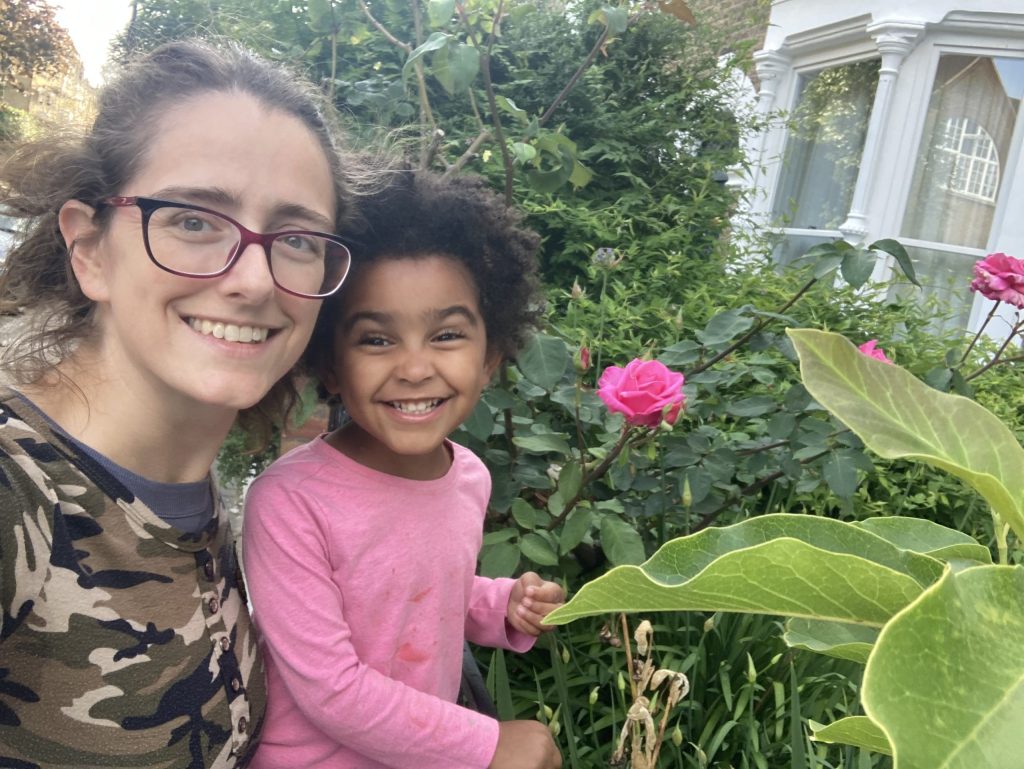 Thea Jaffe with her toddler daughter standing outside looking at some plants.