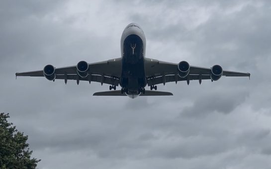 A large plane flying over Heathrow airport.