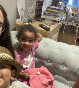 An image of Thea Jaffe, a working mother, with her three children sitting on a sofa in their home.