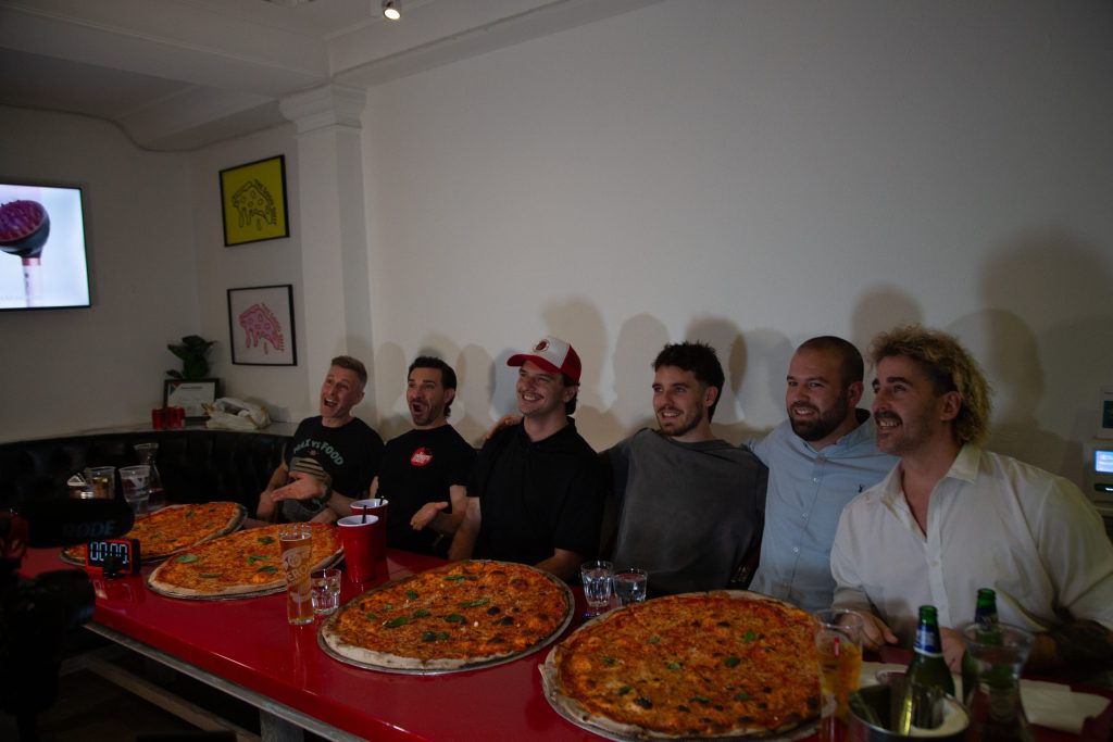 Competitive eaters and hockey players with pizza in front of them