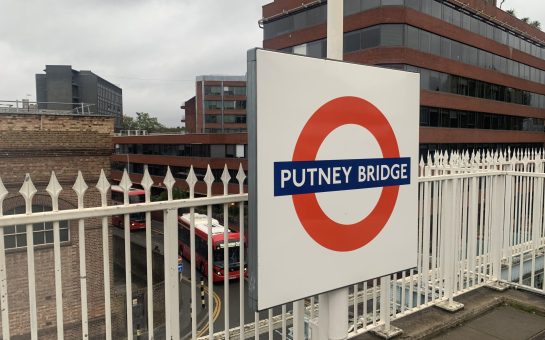 Putney bridge station tube station sign with a london bus in the background