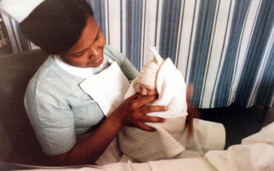 Picture of nurse Joan Andall holding a baby from the BCA archival collection