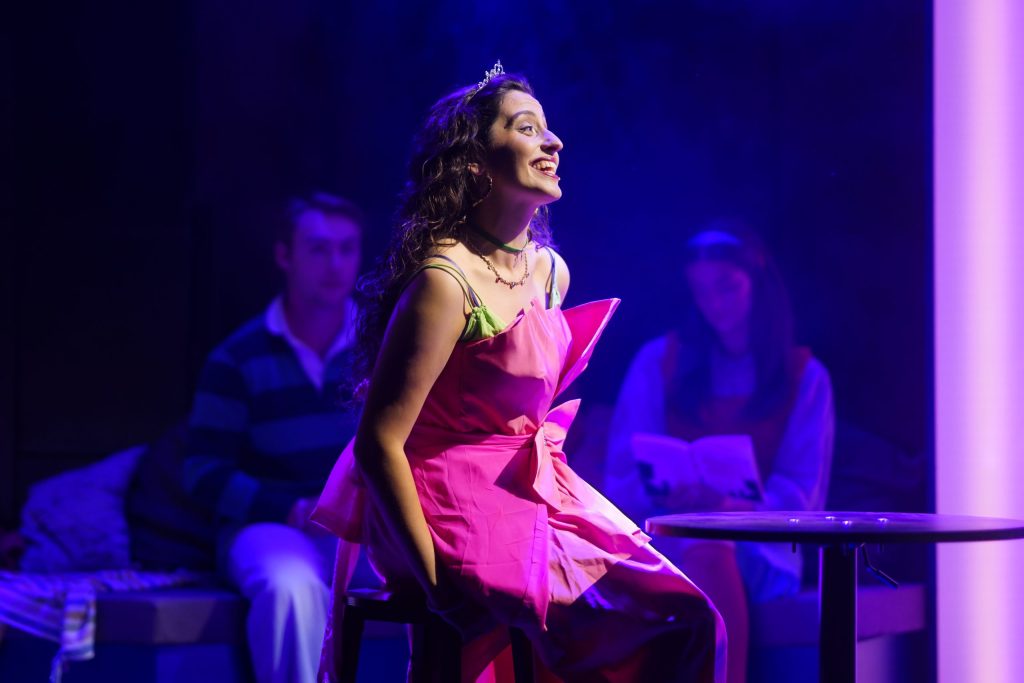 Woman sits on a bench and sings for London musical Love Quirks