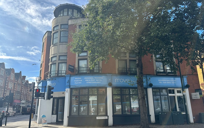 the front of Move Physio in Twickenham. One the corner of a road with a round front, big windows and a blue strap with the company name around the top.