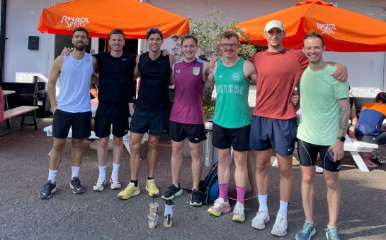 A photo of seven men with their arms around one another after a run