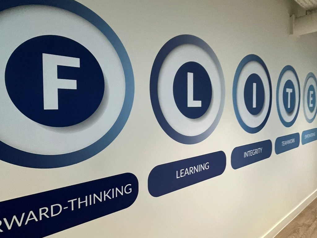 Hawk Training's FLITE valute on the wall of the office with the first letter of each in a blue circle and the full word below