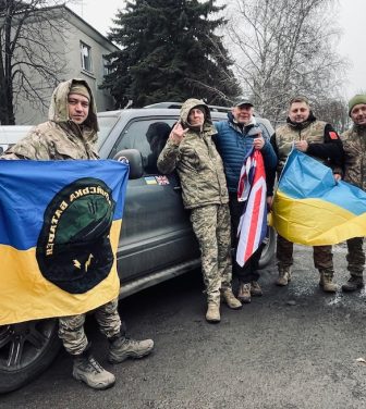 Adrian Simpson alongside Ukrainian troops holding British and Ukrainian Flags