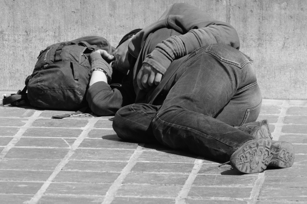 A black and white photo of a person sleeping on the street