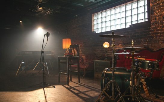A dimly lit music room with a drum kit and a microphone.