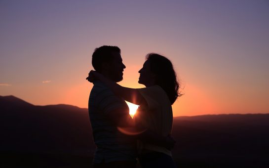 Couple holding each other in front of a sunset