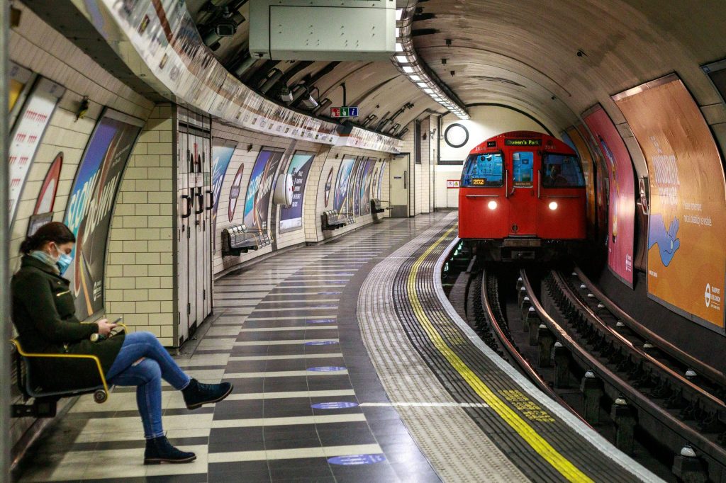 a man sitting on a bench next to a train on the london underground
