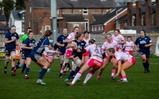 A women's rugby match on a pitch.