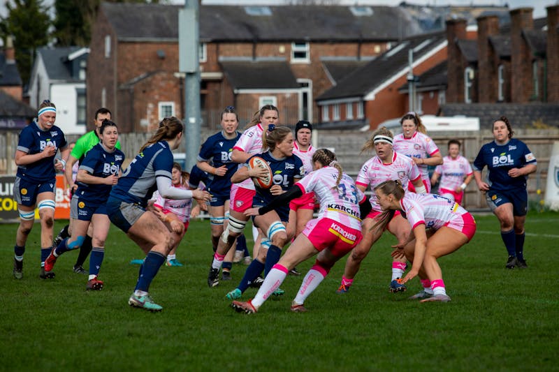 A women's rugby match on a pitch.