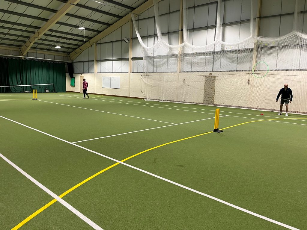 An indoor tennis court with a set of cricket stumps