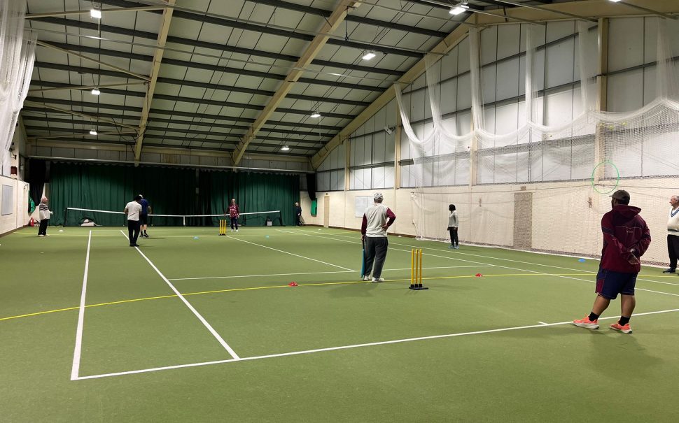 People playing cricket on an indoor tennis court
