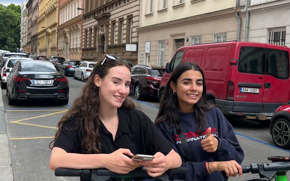 Two young women on e-scooters in London.