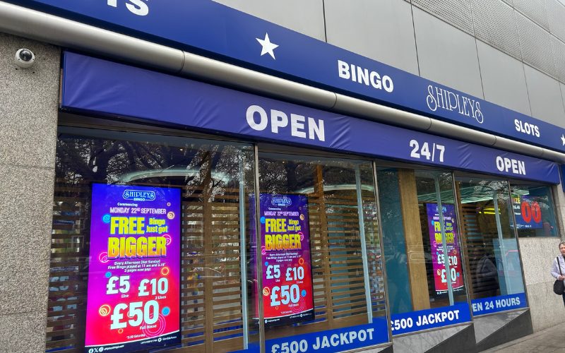 The outside of the 24-hour bingo hall. There are flashy adverts and signs saying 'open 24-hours' .