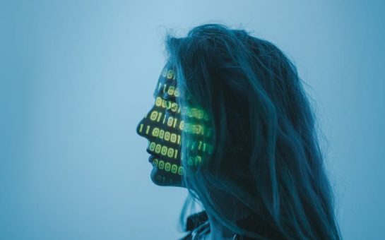 A side profile of a woman with green binary code projected onto her face.
