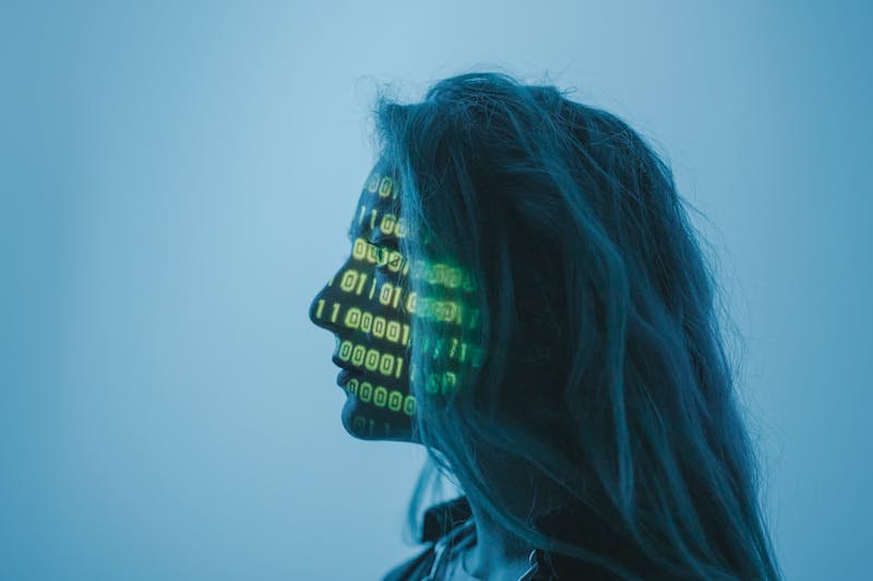 A side profile of a woman with green binary code projected onto her face.